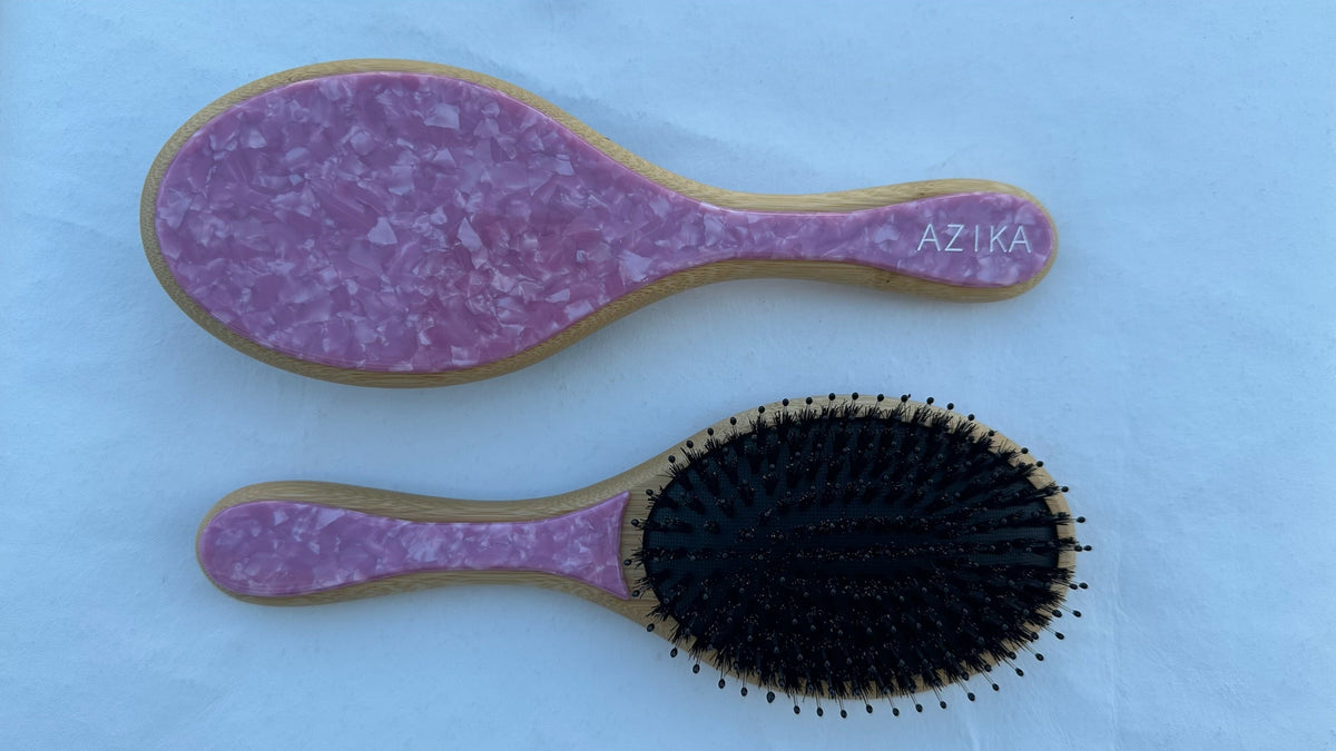A collection of round brushes with boar and nylon bristles in various colors: blue, pink, green, and beige, each with a bamboo handle.