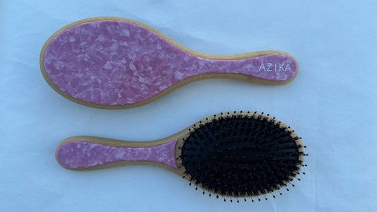 A collection of round brushes with boar and nylon bristles in various colors: blue, pink, green, and beige, each with a bamboo handle.